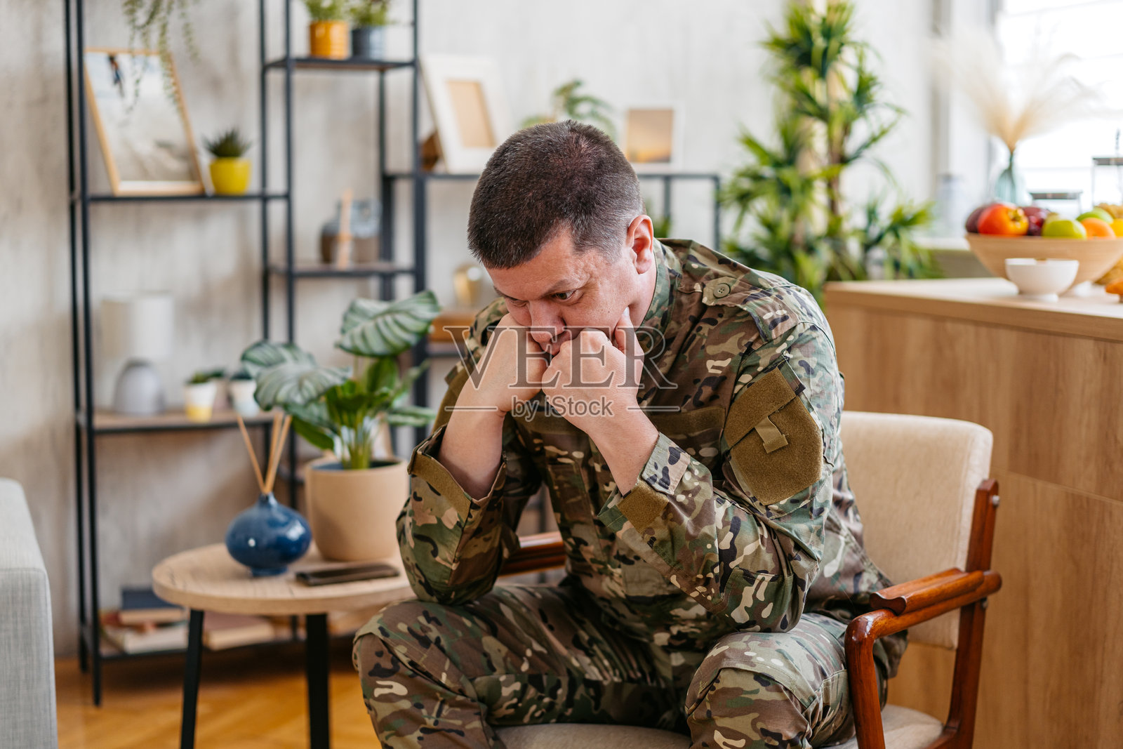 沮丧的中年士兵穿着军装坐在客厅的椅子上照片摄影图片