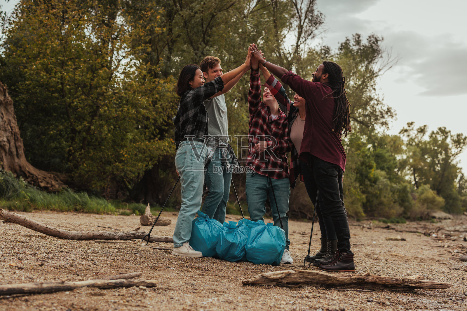 志愿者在河岸捡垃圾后手拉手团结在一起照片摄影图片