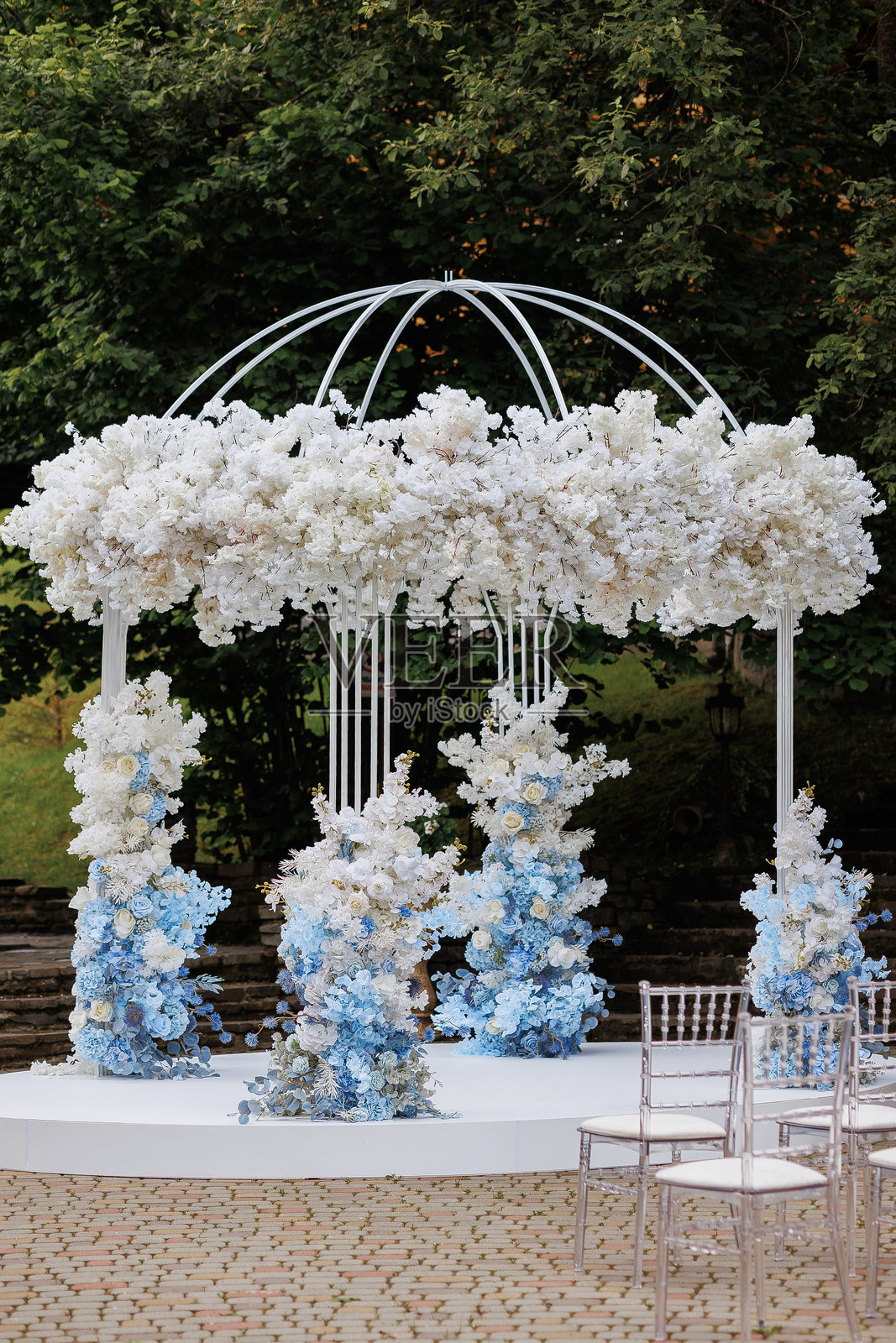 婚礼仪式在一个大型白色和蓝色的伞下进行。照片摄影图片