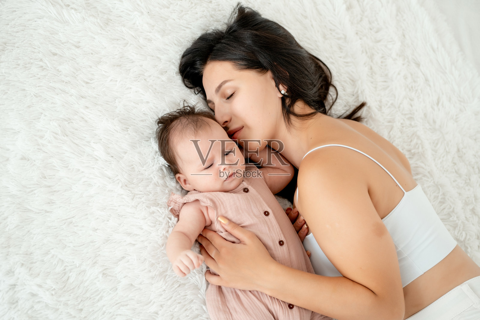 妈妈在明亮的卧室里哄宝宝入睡,温柔地拥抱着新生儿,充满母爱与关怀。照片摄影图片