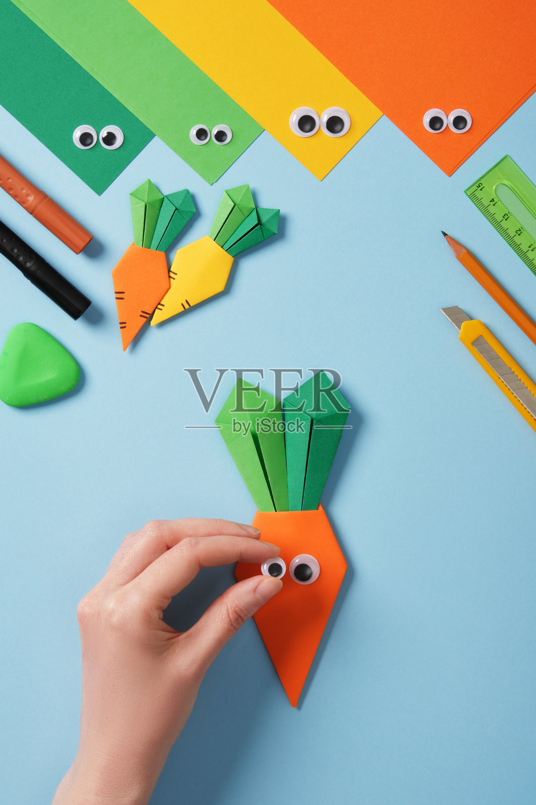 制作折纸胡萝卜。DIY项目。粘贴或画上眼睛。照片摄影图片