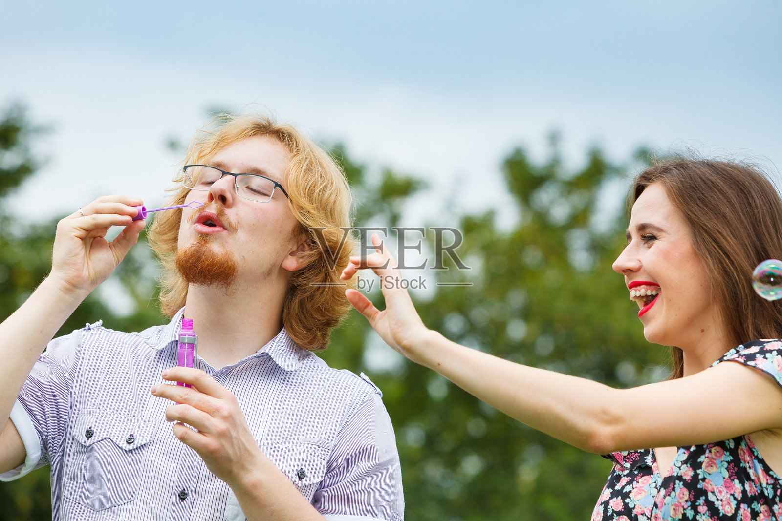 一对情侣在玩耍,吹着肥皂泡。照片摄影图片