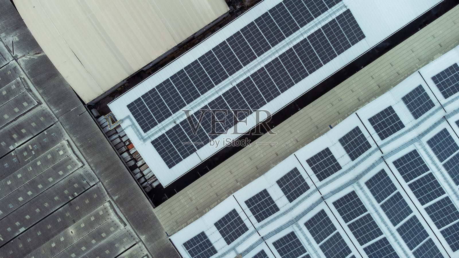 建筑物屋顶上安装了多个太阳能电池板。太阳能电池板整齐地排列成行和列,每个电池板之间有明显的间隔。照片摄影图片