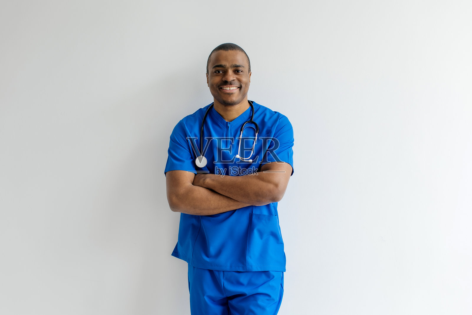 穿着蓝色护士服或医生服的非裔美国男性护士或医生,双臂交叉。照片摄影图片