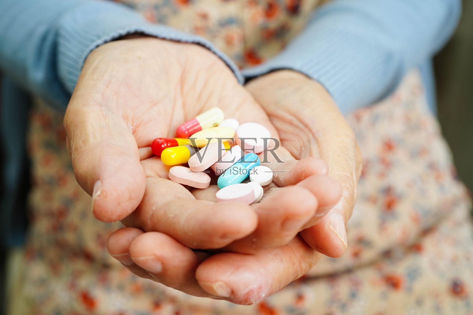 亚洲老年女性手中握着药丸,健康强壮的医疗形象。照片摄影图片