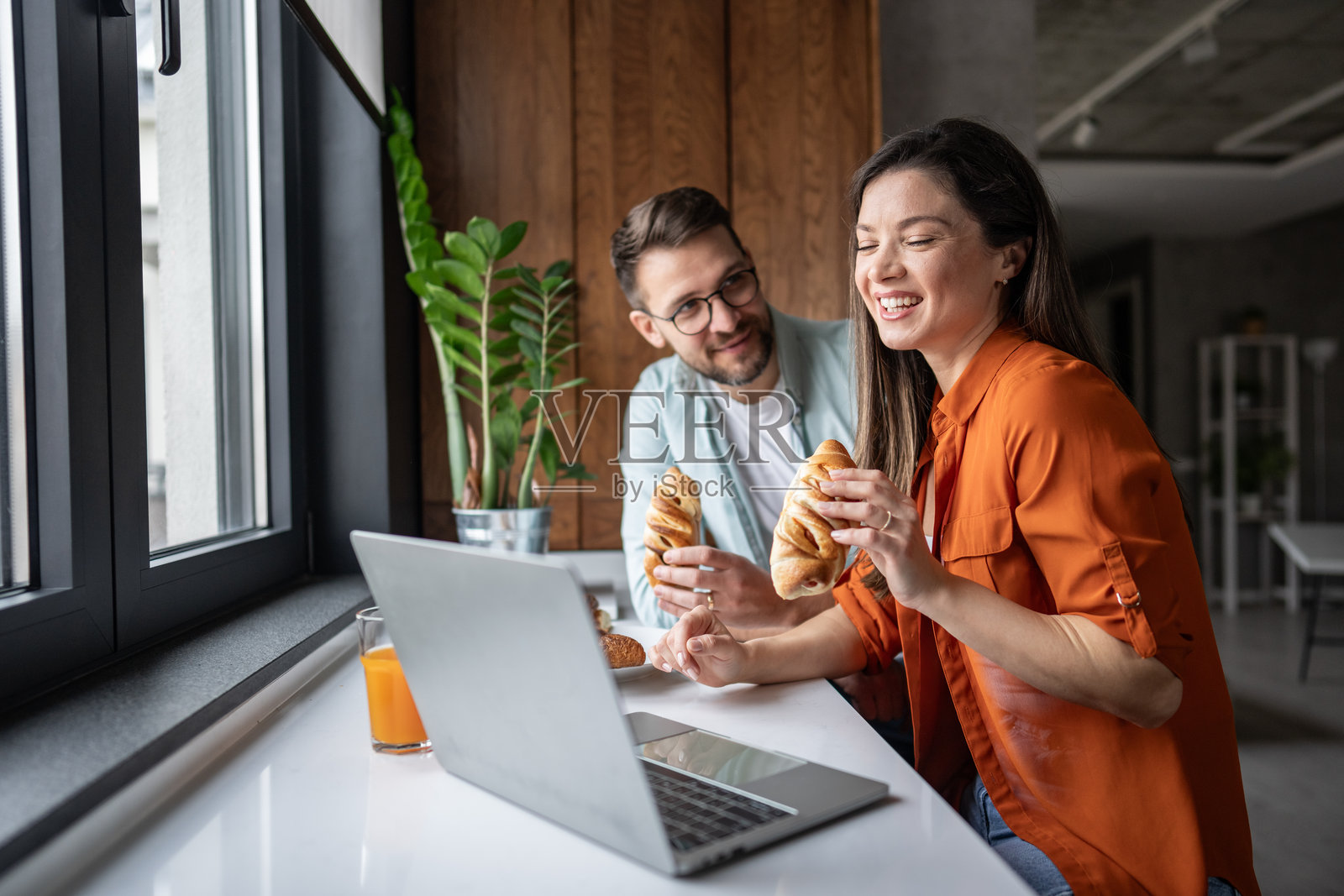 一对情侣在吃早餐时观看笔记本电脑上的内容照片摄影图片