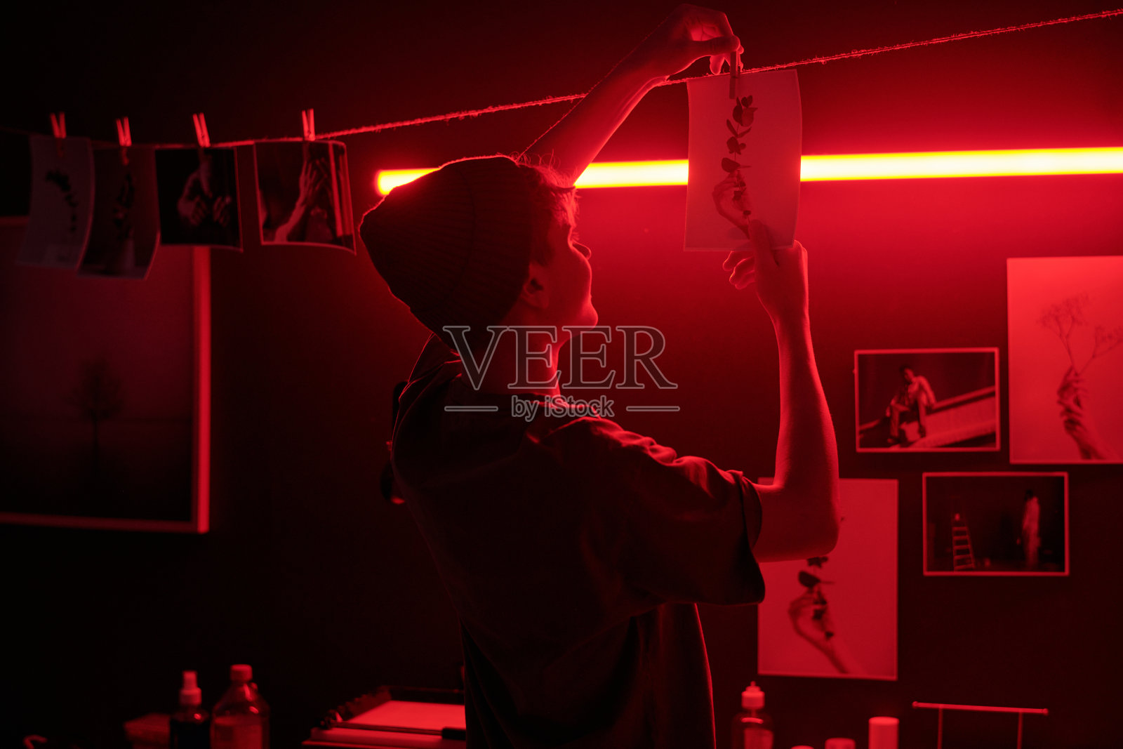 摄影师在暗房中悬挂照片打印的红光图像照片摄影图片