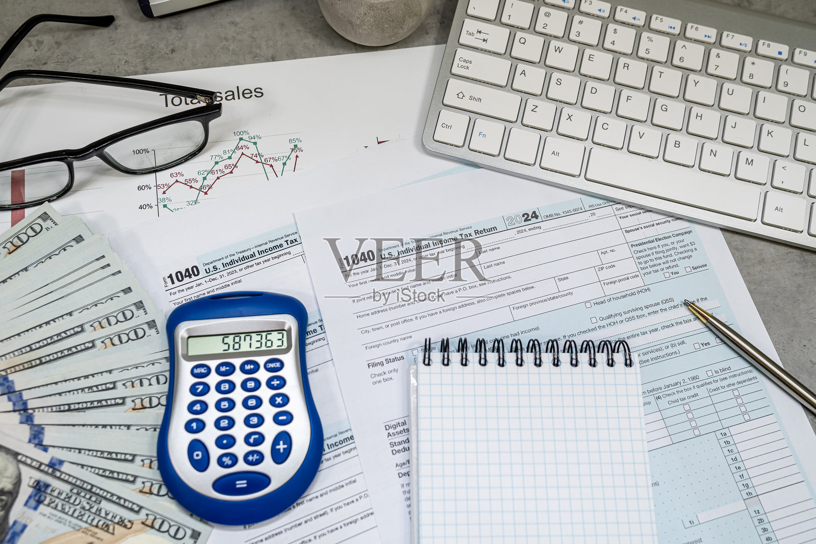 1040美国税表、笔、计算器和美元眼镜放在桌子上。税收、缴纳税率。四月时光。照片摄影图片