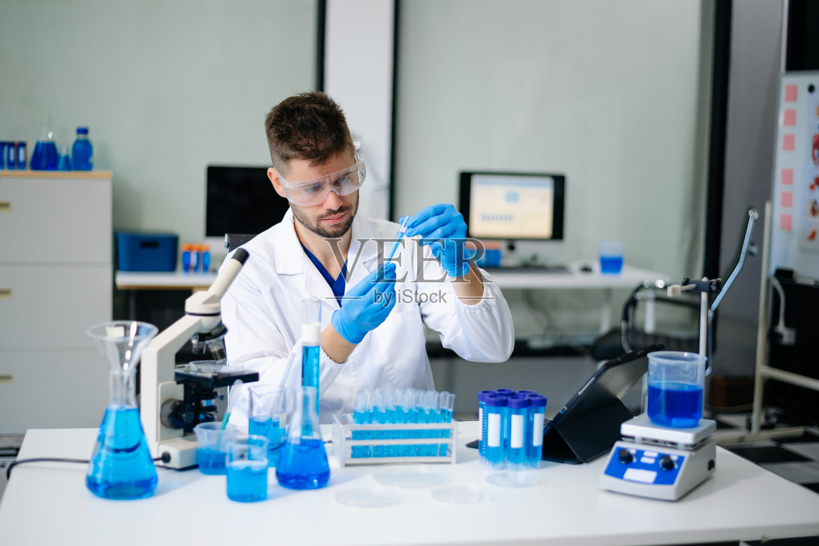 穿着实验室外套的科学家们正在进行研究,处理玻璃器皿和化学品。照片摄影图片