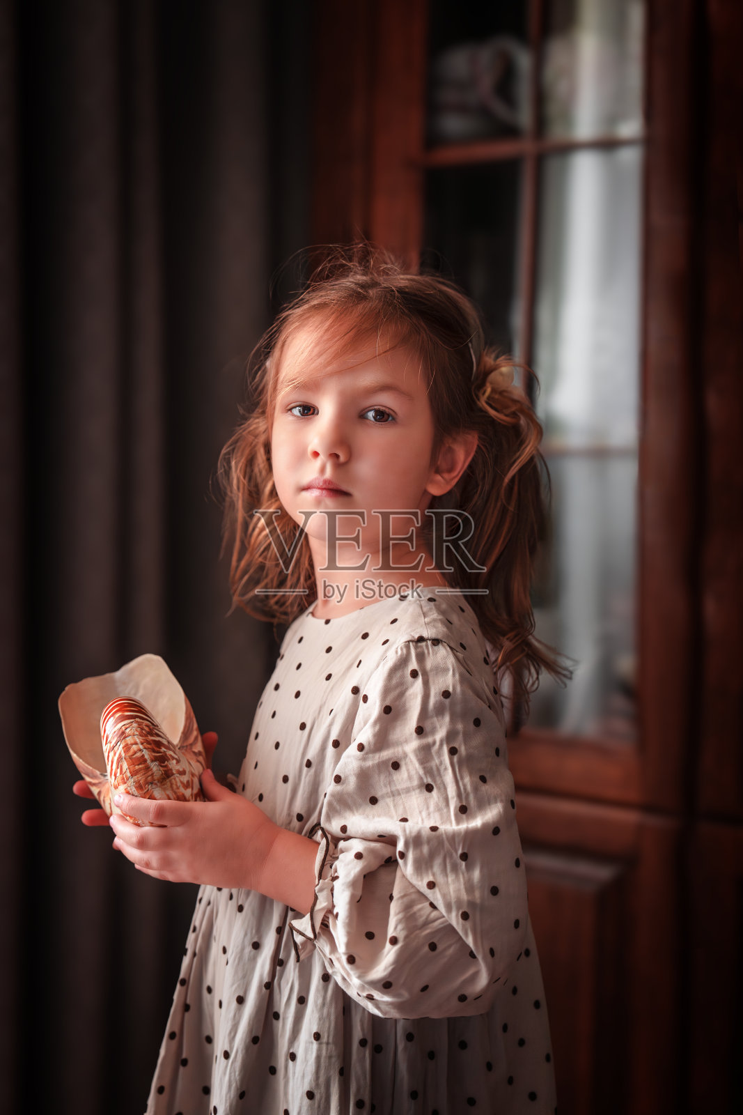 可爱的小女孩手捧贝壳,面向镜头微笑照片摄影图片