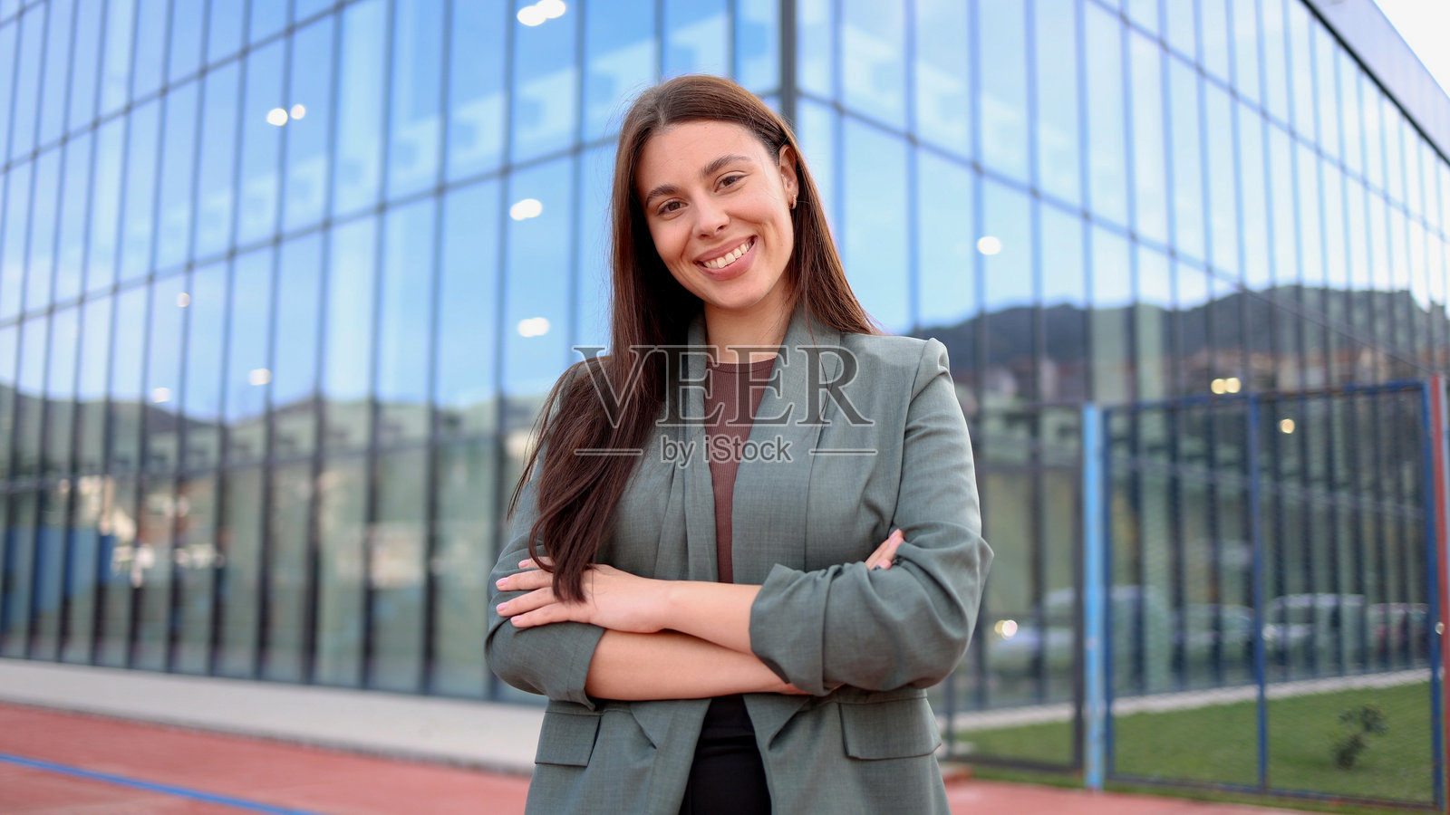 微笑的女商人在现代办公大楼前交叉双臂照片摄影图片