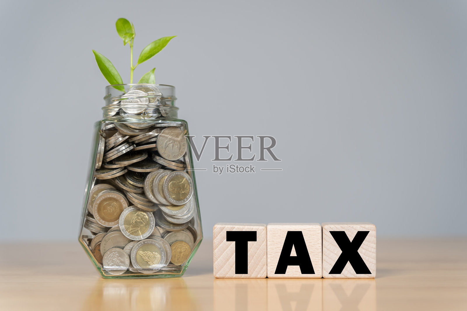 一个标有“税”的罐子,里面装满了硬币和木块,代表储蓄和财务规划的概念。照片摄影图片