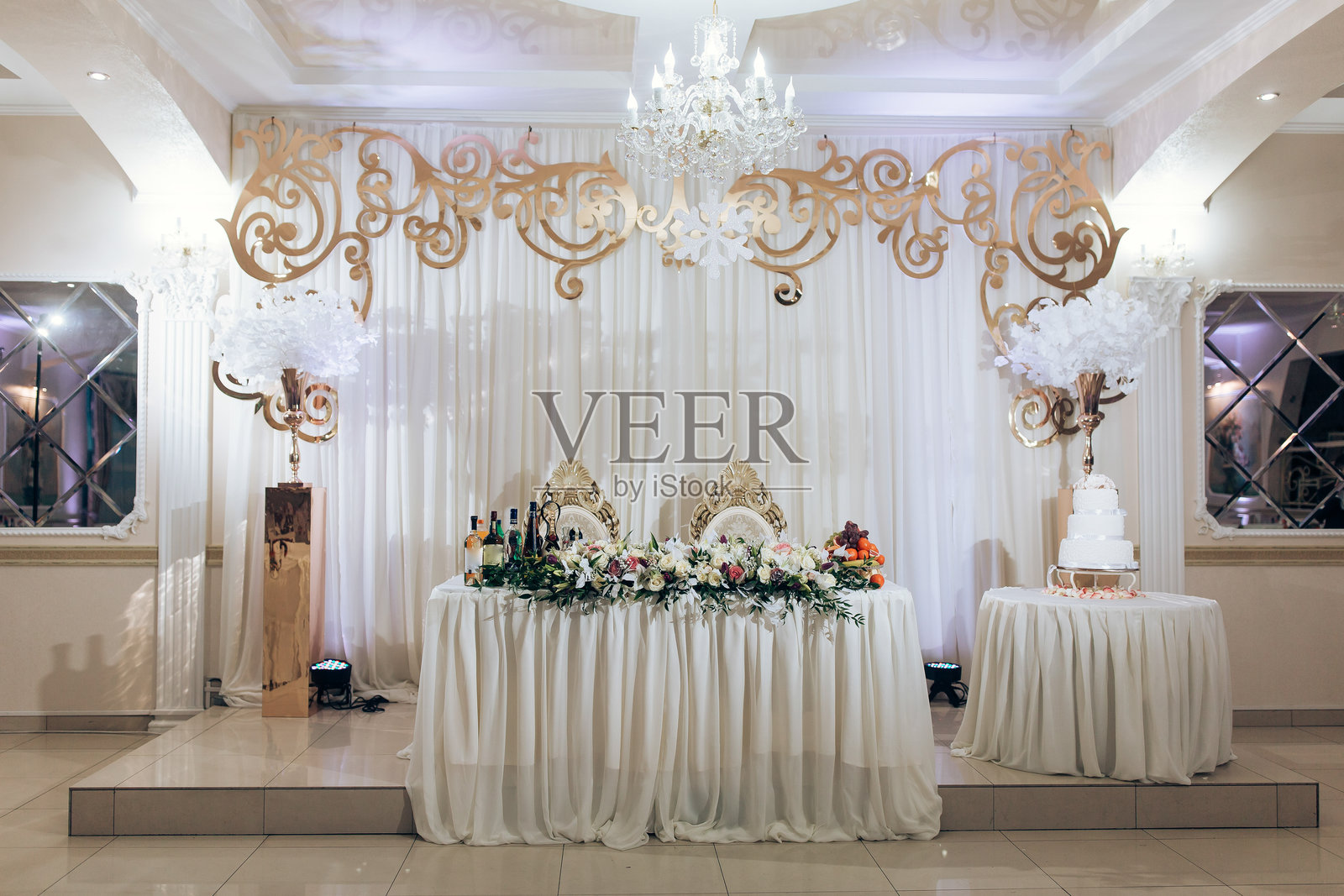 一张大白色桌子上方悬挂着一个吊灯,桌子上放着一个蛋糕。照片摄影图片