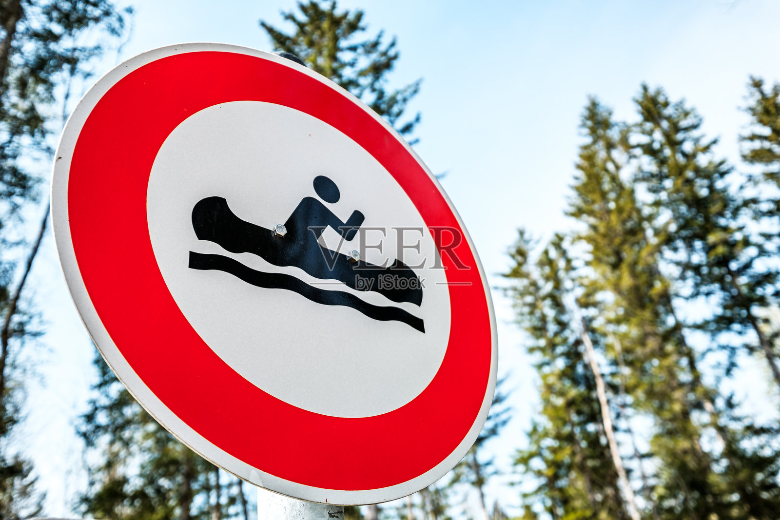 禁止在白天时段于河流附近划独木舟的标志,周围环绕着郁郁葱葱的森林照片摄影图片