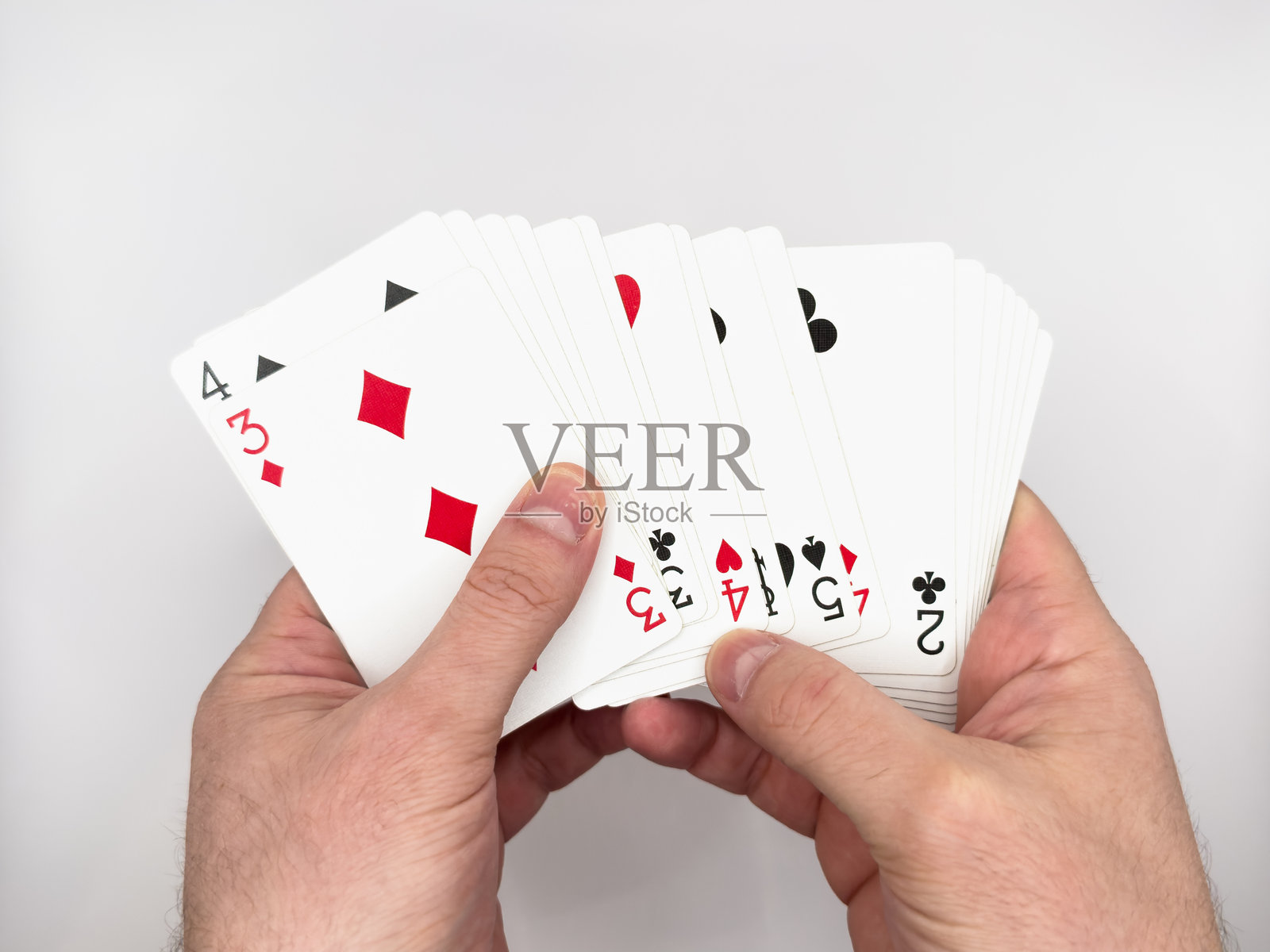 白人男性的手在白色背景中央展示白色塑料扑克牌照片摄影图片