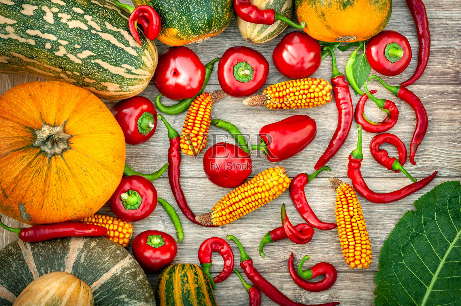 收获蔬菜。木质背景上的南瓜、玉米、红椒和青椒。照片摄影图片