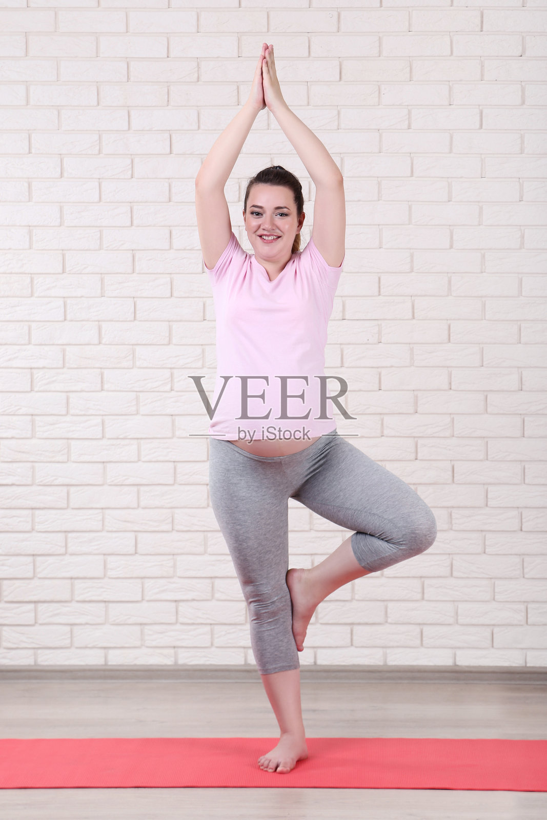 年轻孕妇在砖墙背景下做运动照片摄影图片