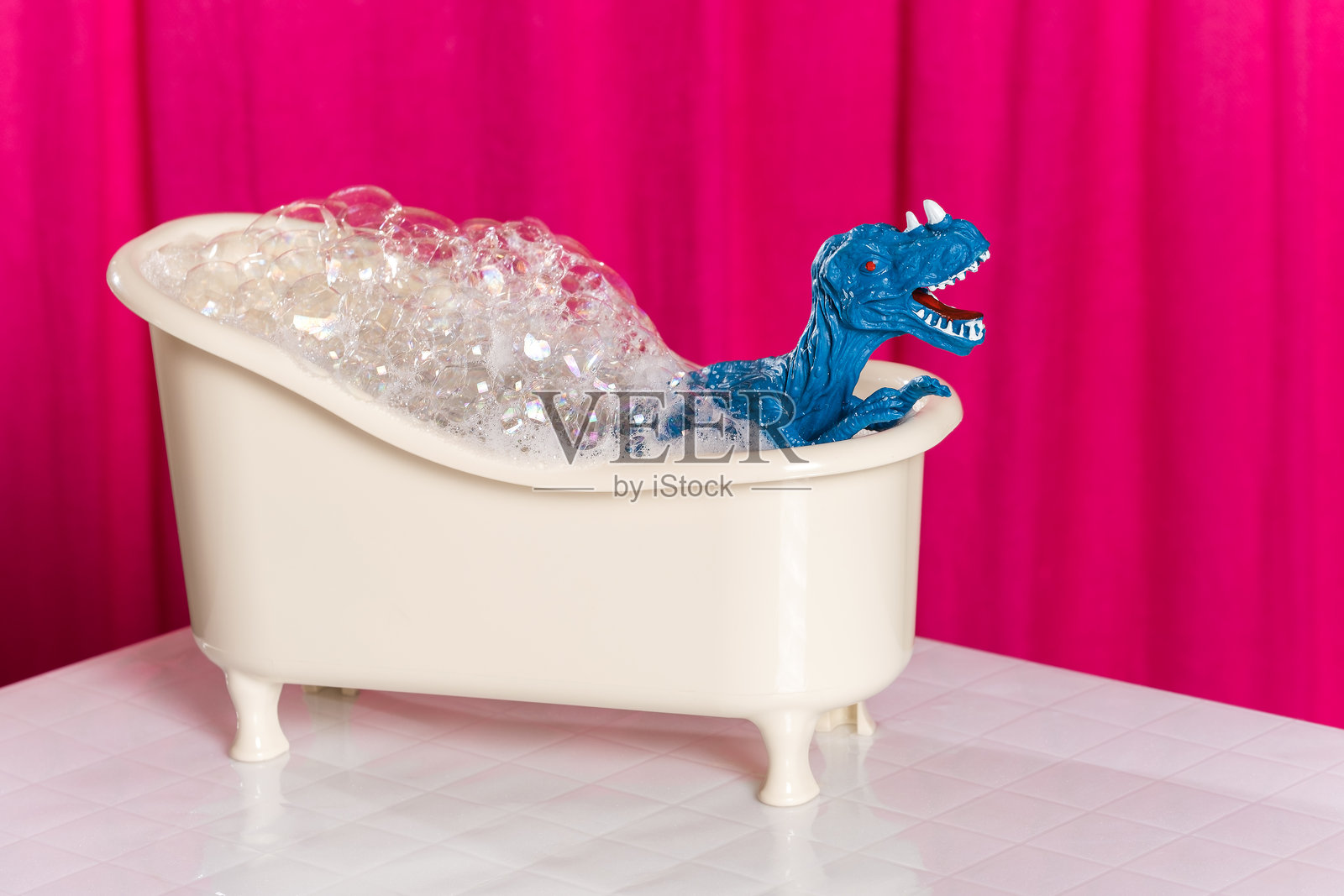 可爱的蓝色恐龙在充满泡沫的浴缸里洗澡,背景是粉色窗帘。儿童浴室海报概念。照片摄影图片