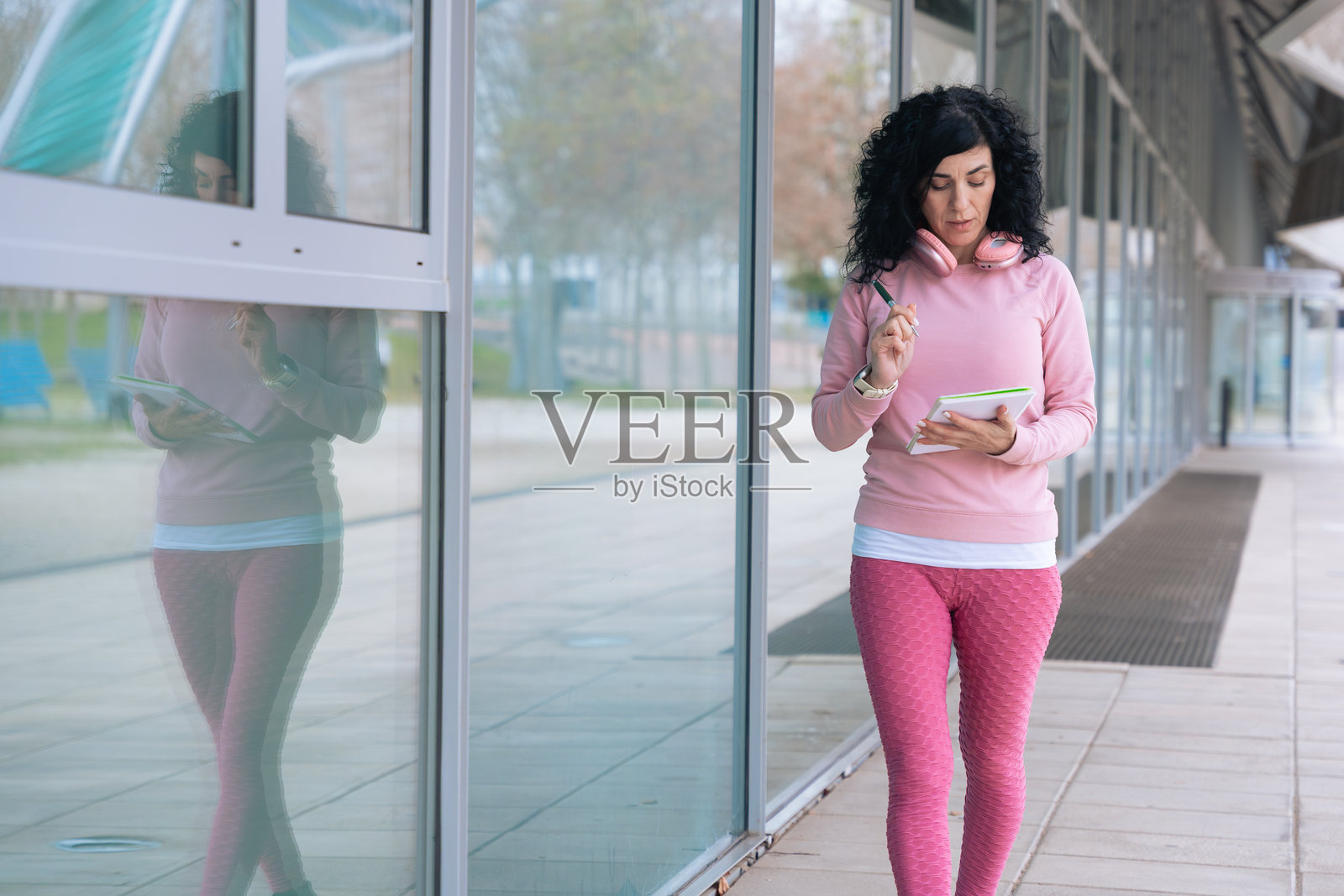 白人运动女性在走路时写笔记本,旁边留有空白空间照片摄影图片