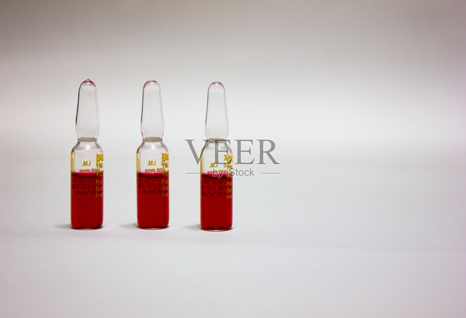 安瓿药物和装满红色药物的注射器。疫苗接种和药物概念。孤立的安瓿和疫苗。维生素B,留白空间。B12药物。照片摄影图片
