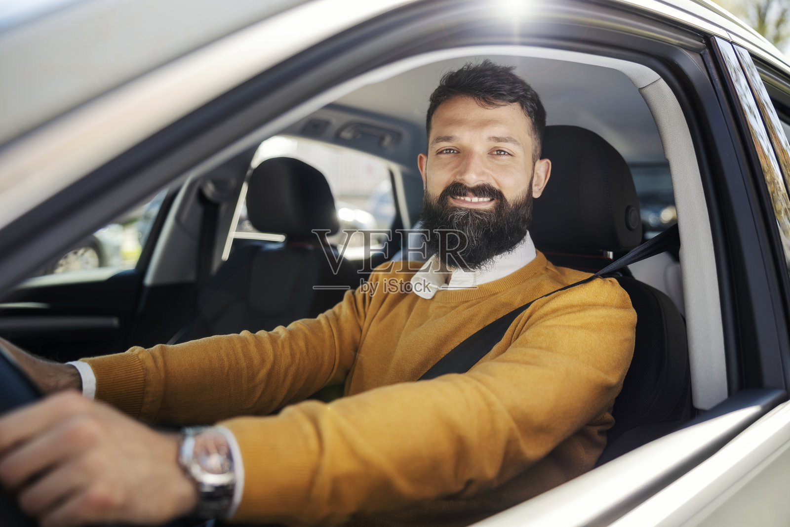 年轻商人在车内坐着,双手握住方向盘,面带微笑看向镜头。照片摄影图片