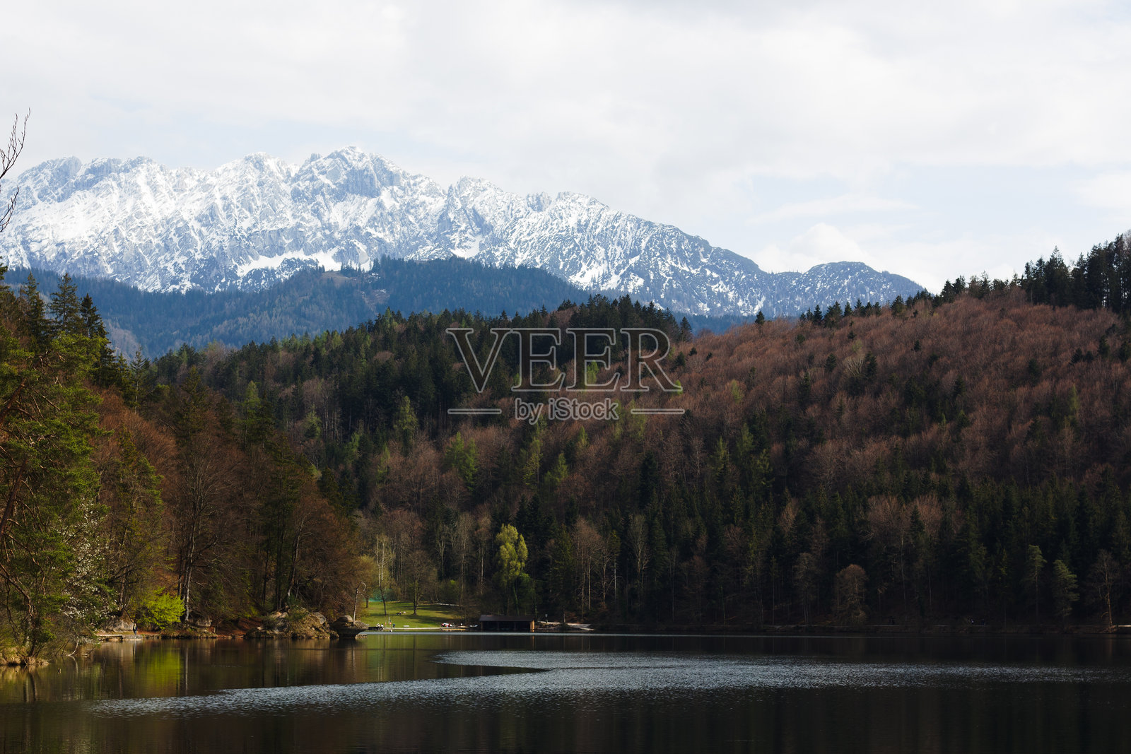 宁静的赫赫特湖在多云的天空下映照出山脉和森林。照片摄影图片