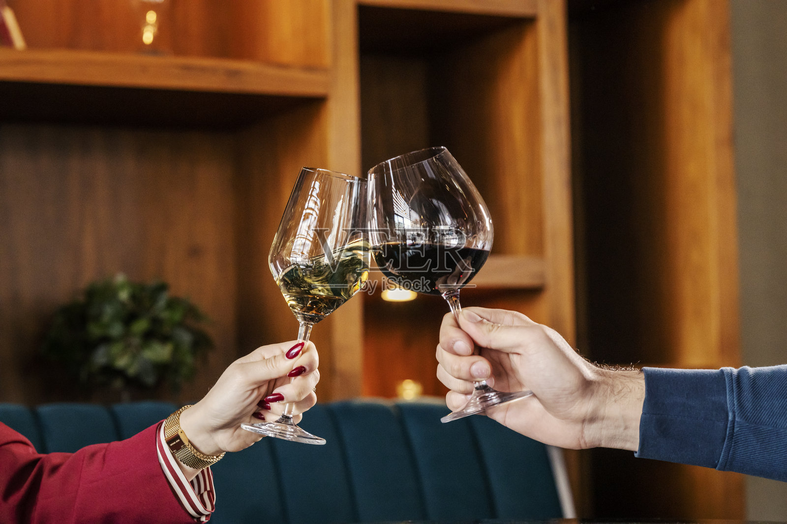 一对情侣的手握着酒杯,举杯祝酒的特写。照片摄影图片
