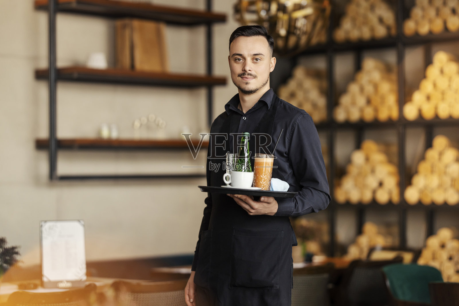 友好的服务员在酒吧里托着饮料和小吃的肖像。照片摄影图片