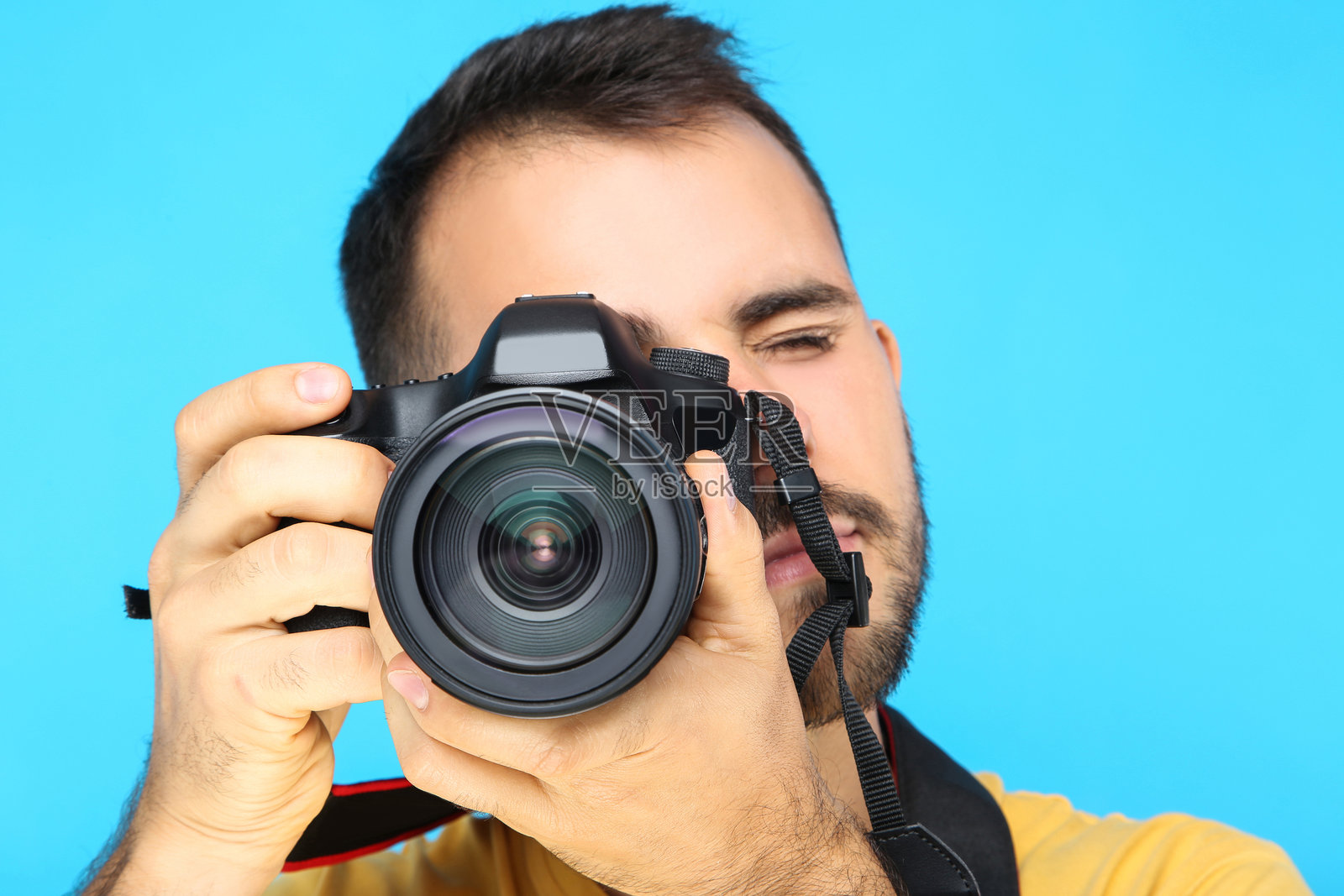 年轻摄影师在蓝色背景下拿着相机照片摄影图片