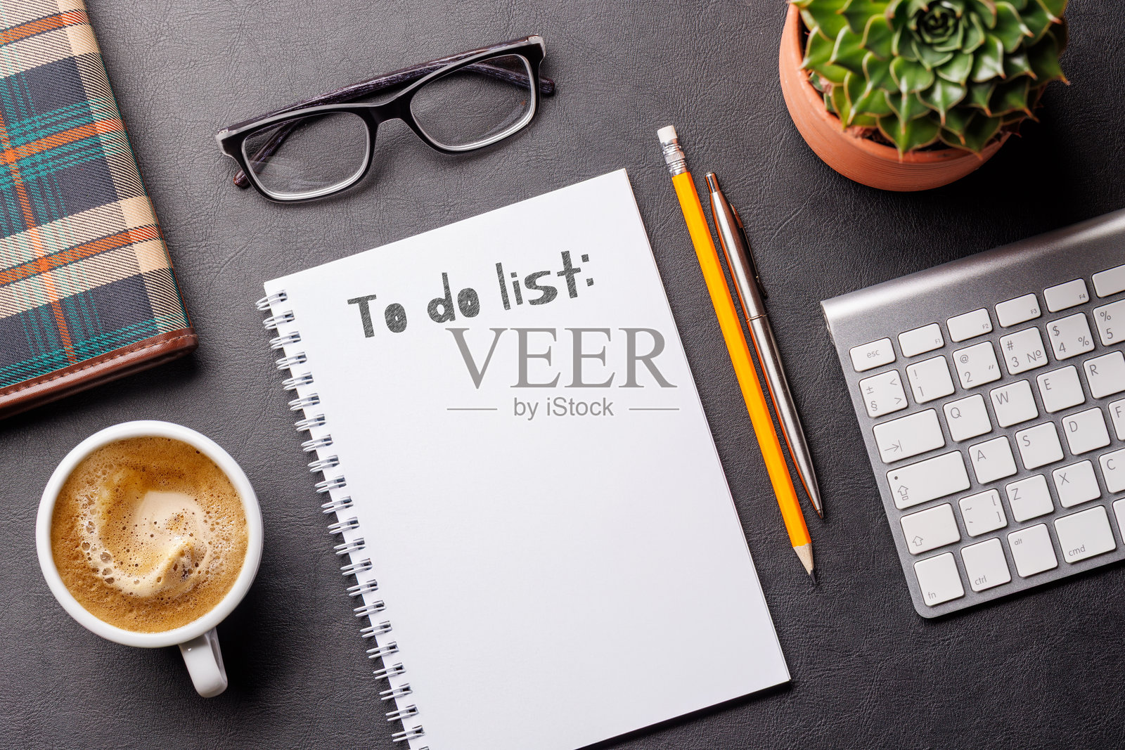 整齐的工作桌面,配有电脑、办公用品、咖啡和用于写待办事项的记事本照片摄影图片