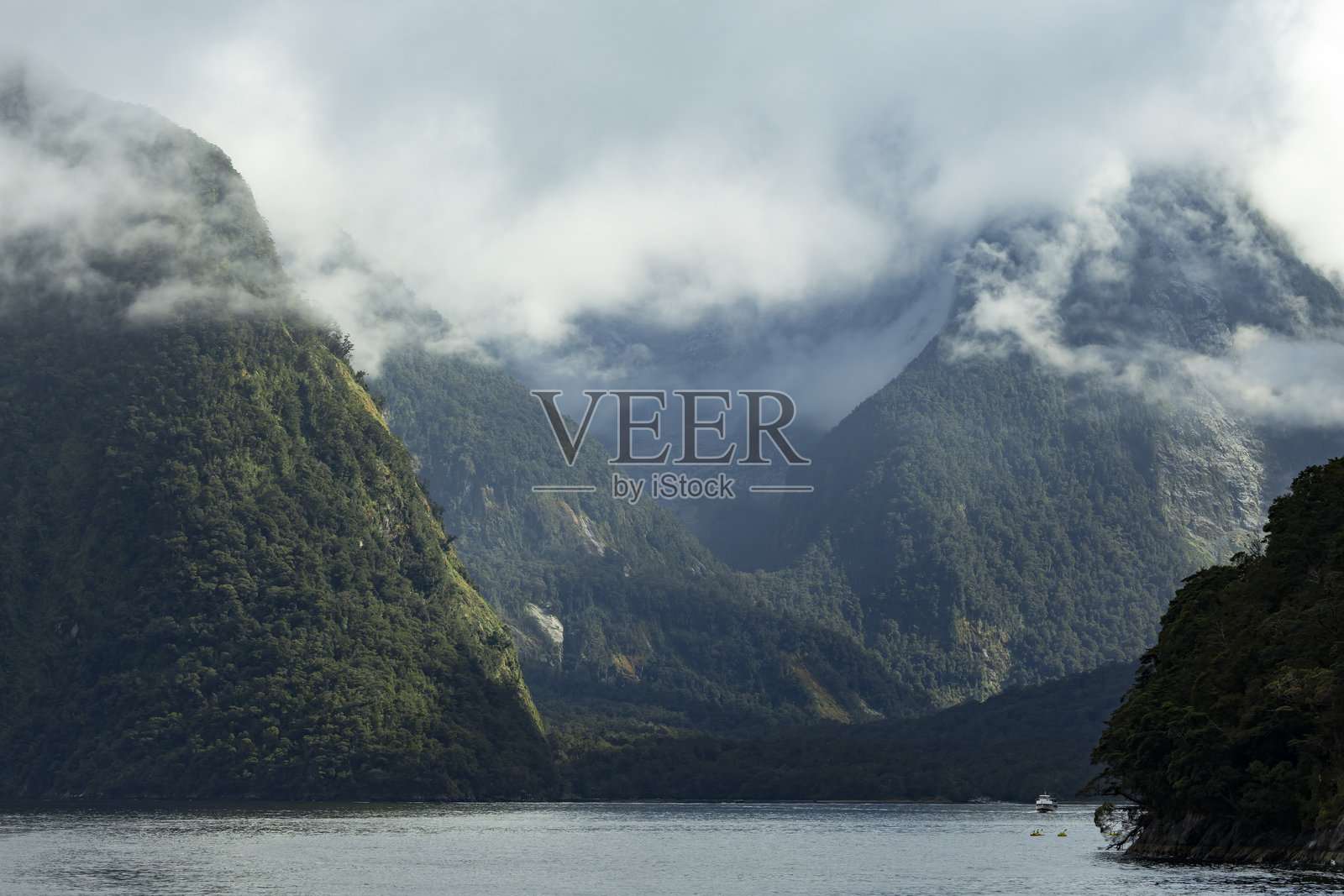 新西兰米尔福德峡湾的多云山景和船只照片摄影图片