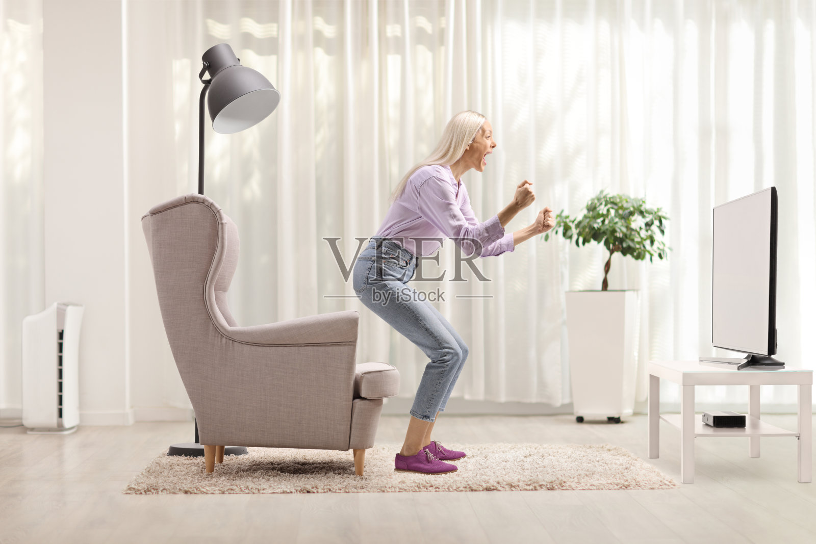 全身侧面照,兴奋的女性在电视前用手势表达。照片摄影图片