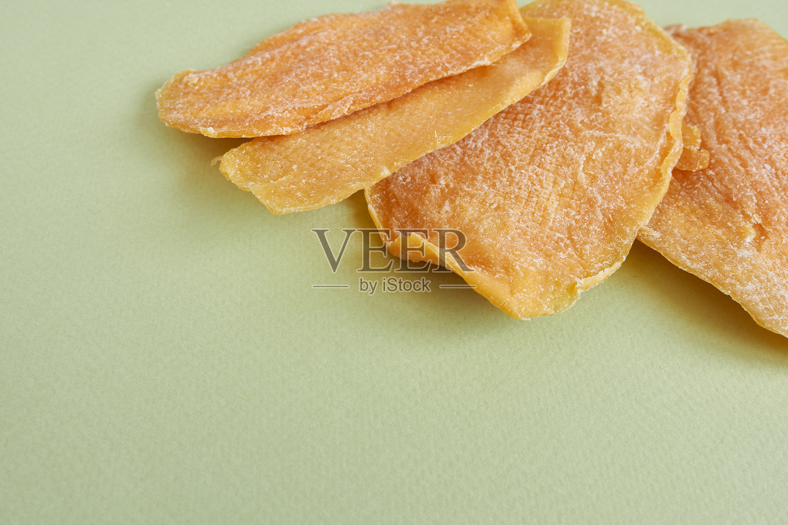 绿色背景上的干芒果片。照片摄影图片