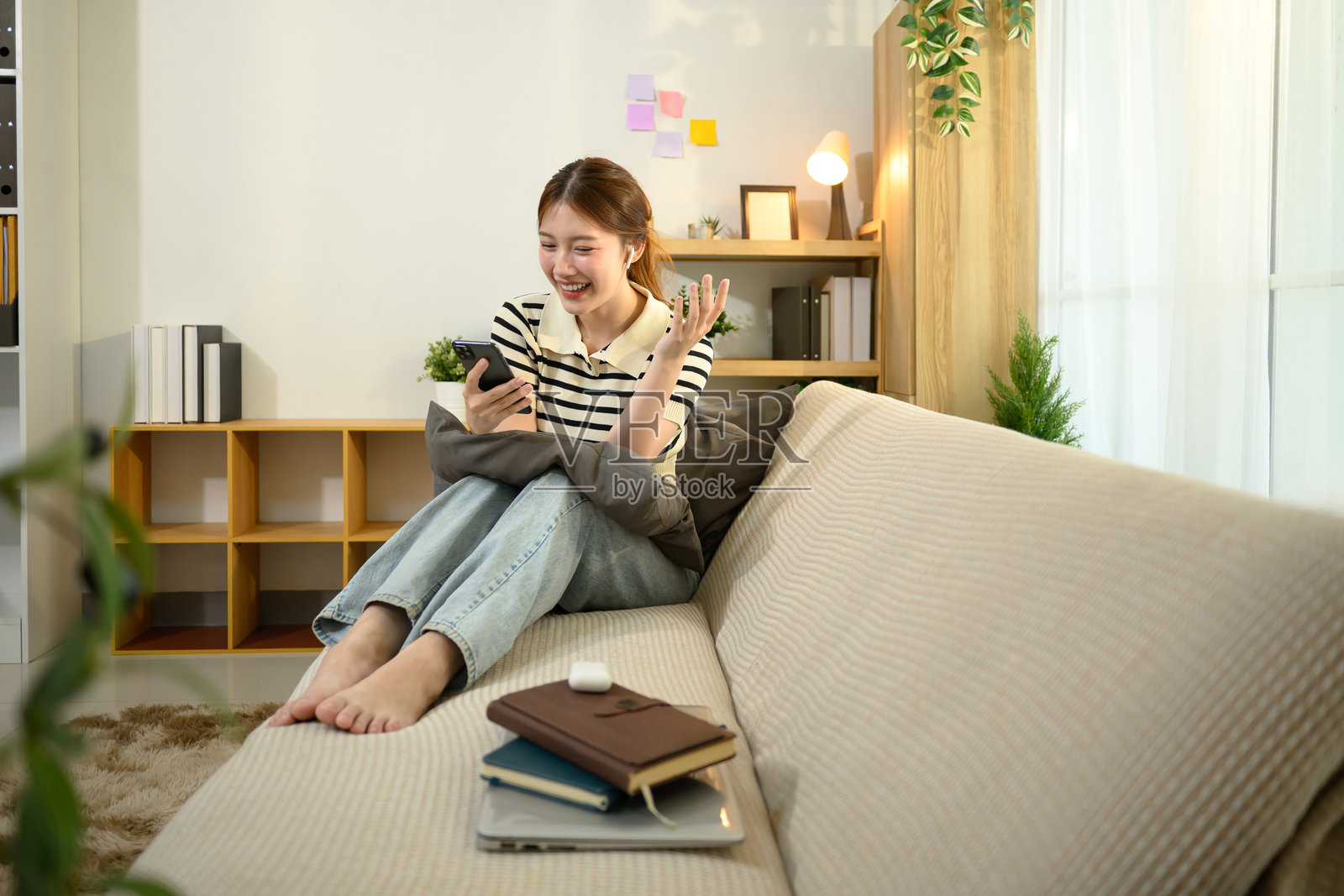 年轻女性在家沙发上微笑着进行视频通话照片摄影图片