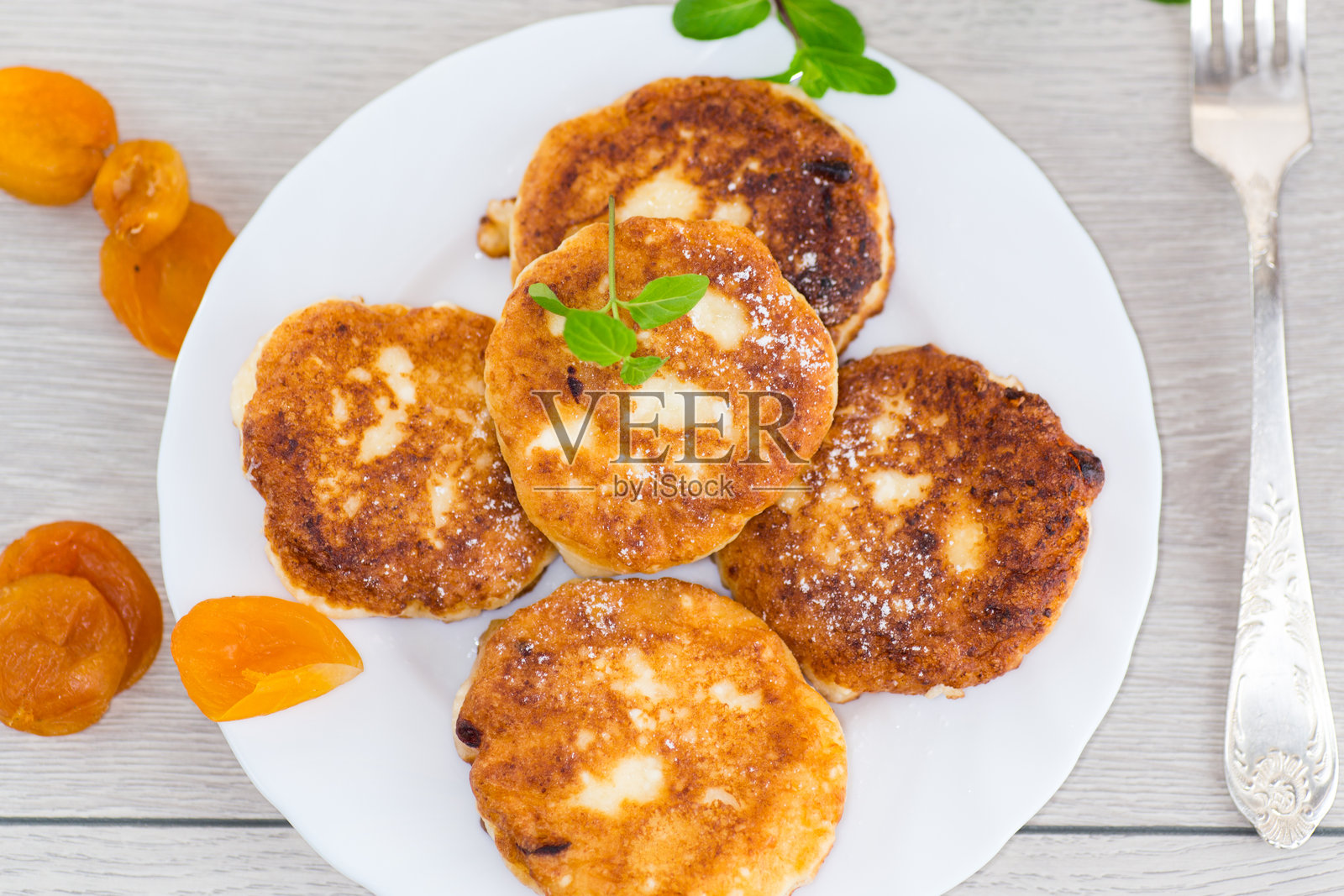 白盘上的红润奶酪煎饼,配有蜂蜜和薄荷照片摄影图片