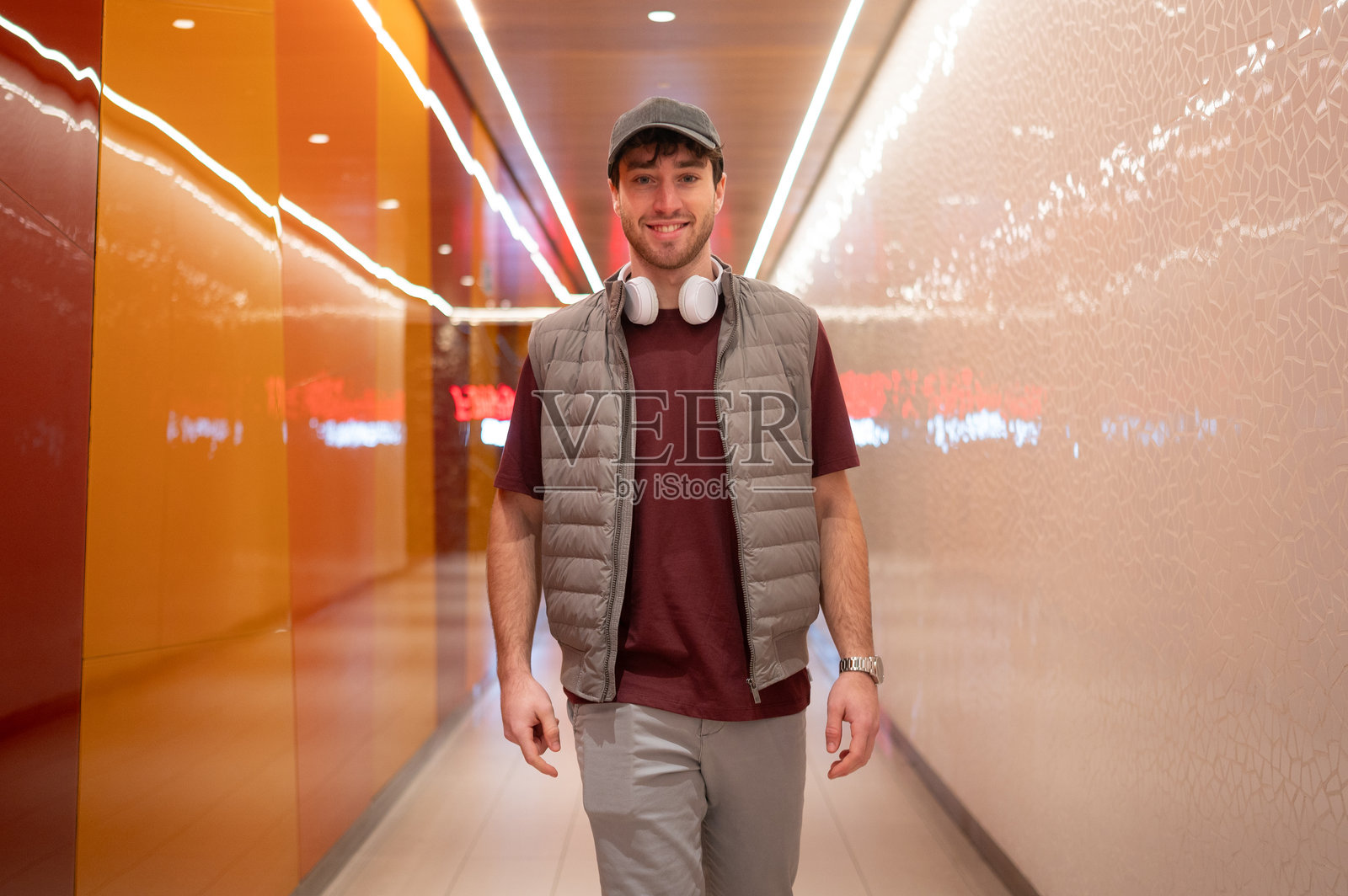 年轻男子在现代走廊中行走,走廊的墙壁色彩斑斓。照片摄影图片