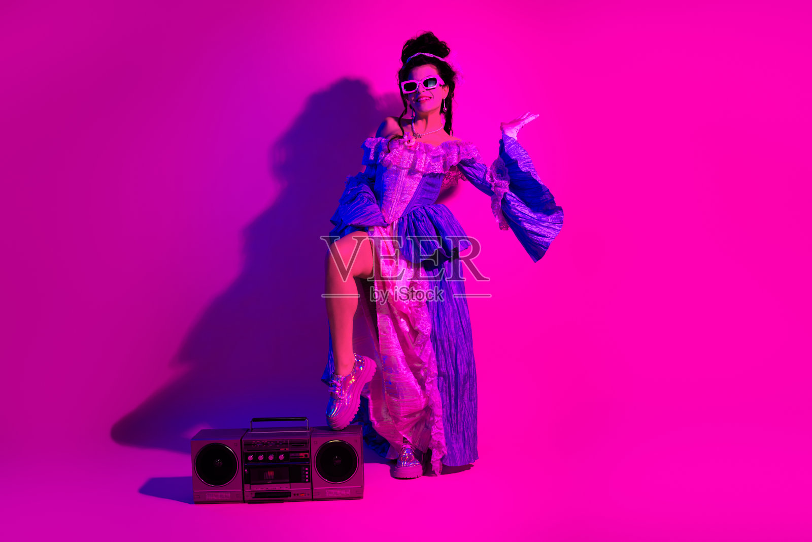 年轻女性穿着复古服装,在充满活力的紫色霓虹背景下庆祝照片摄影图片