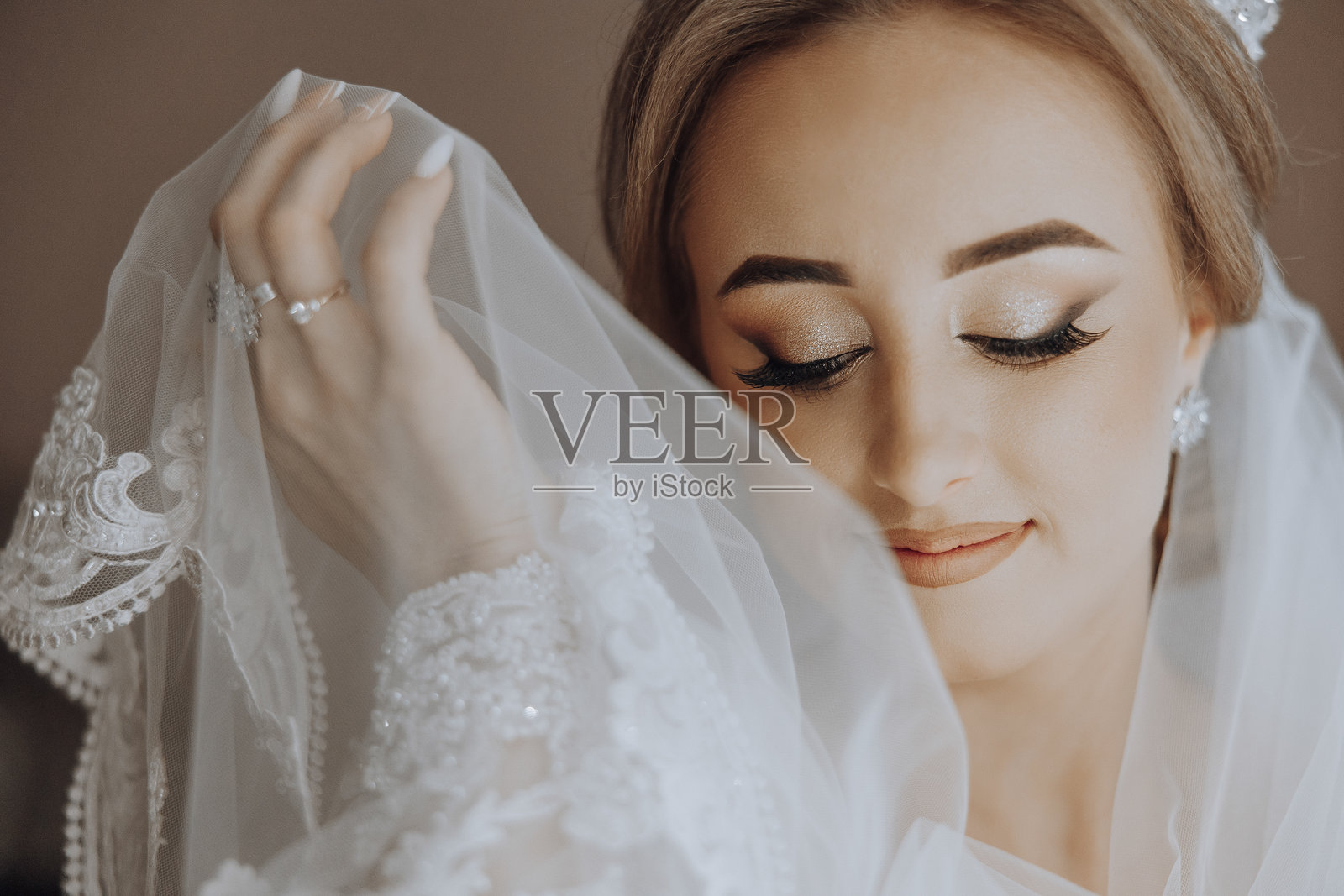 一位女性戴着白色面纱,手指上佩戴着戒指。照片摄影图片