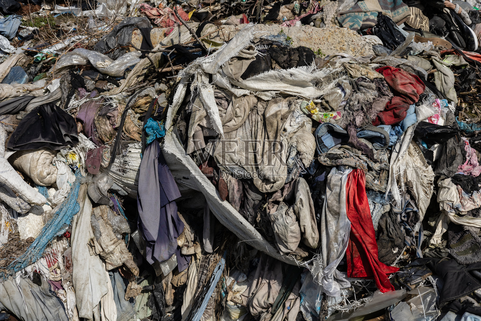 废弃衣物和杂物堆积成山,造成垃圾填埋场的污染隐患,凸显了回收和废物管理的紧迫需求。照片摄影图片