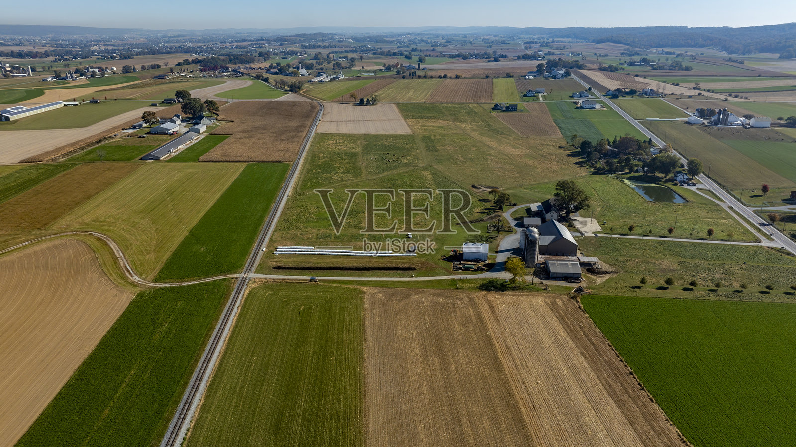 秋季晴空下的广阔农田景观,田野、谷仓和乡村道路交错其中照片摄影图片