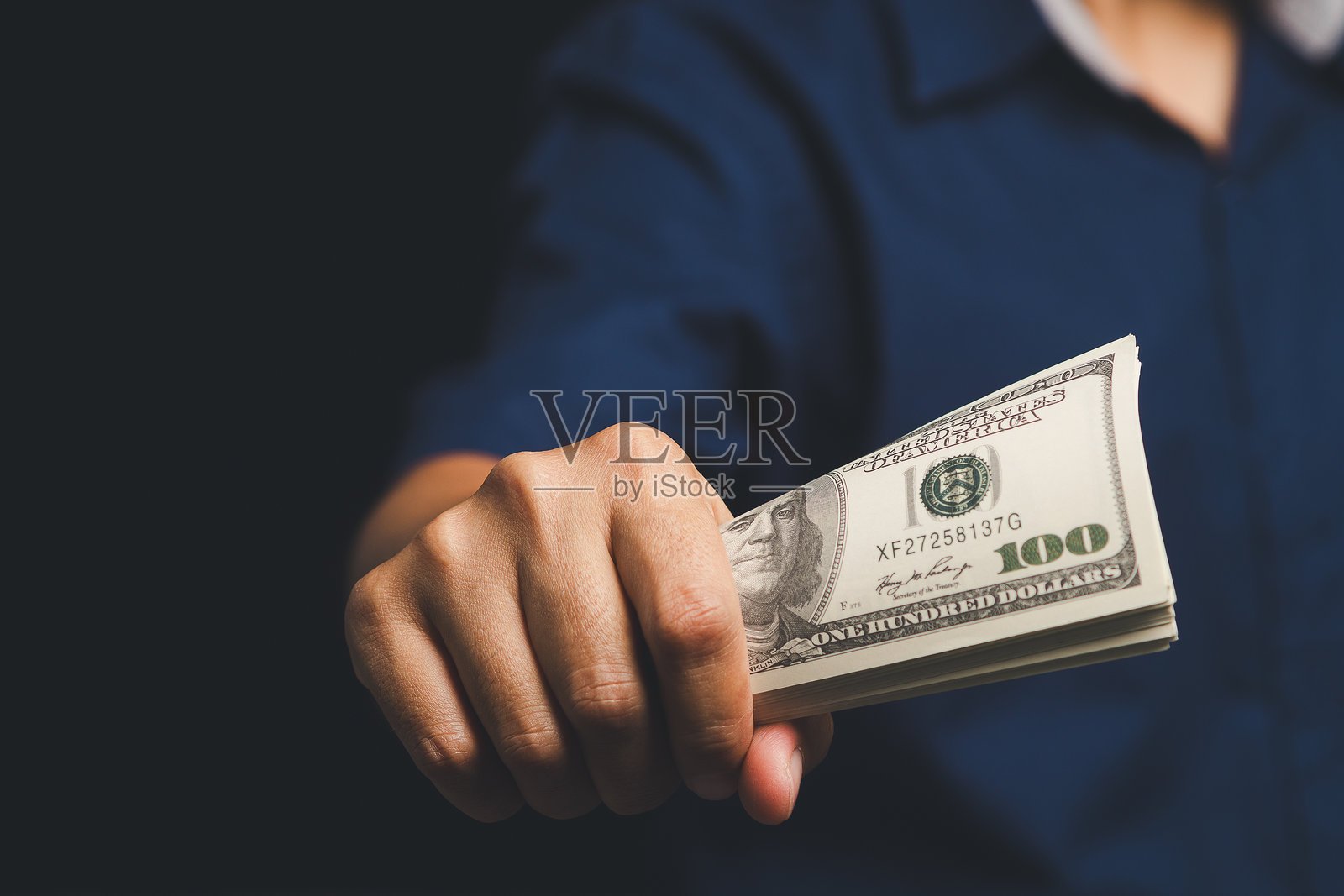 特写镜头展示一只手递出一捆美元现金。照片摄影图片