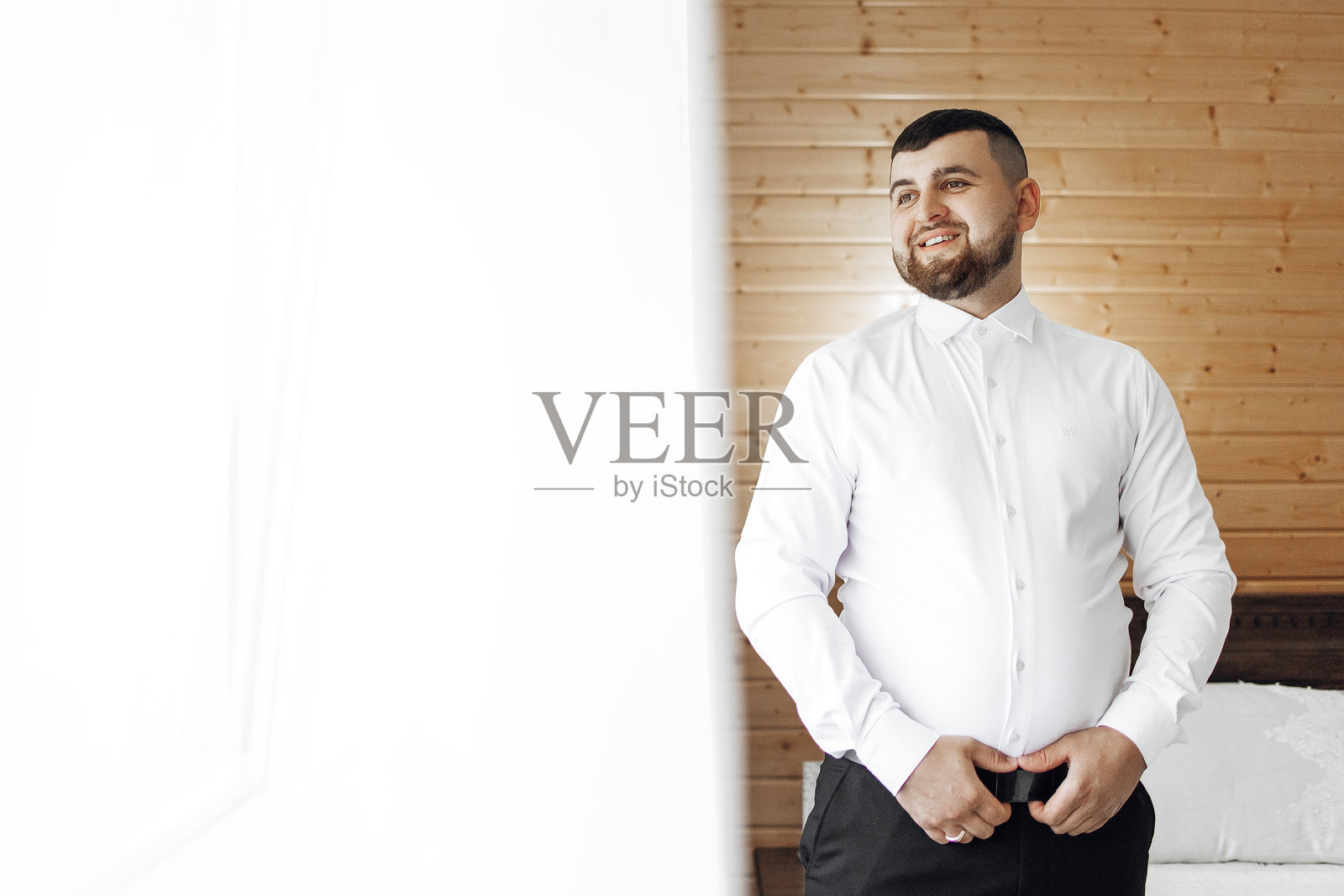 一名穿着白衬衫和黑裤子的男子站在窗前照片摄影图片