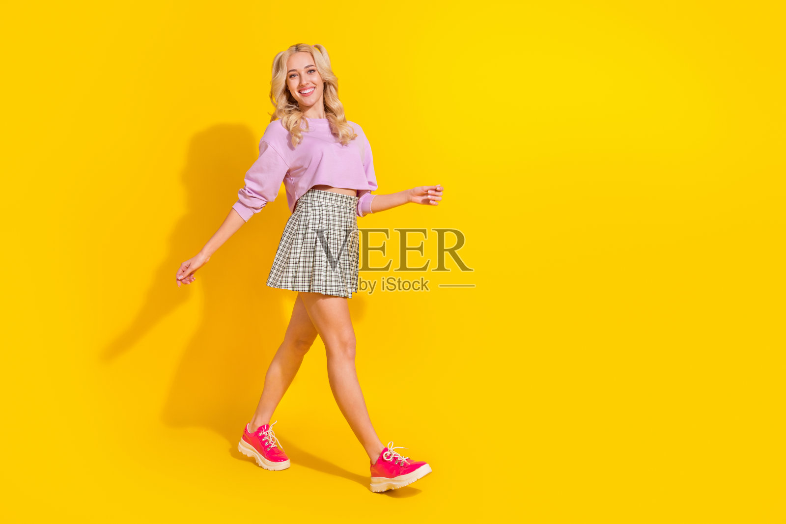 全身侧面肖像,满意可爱的女孩露出灿烂的微笑,背景为黄色。照片摄影图片