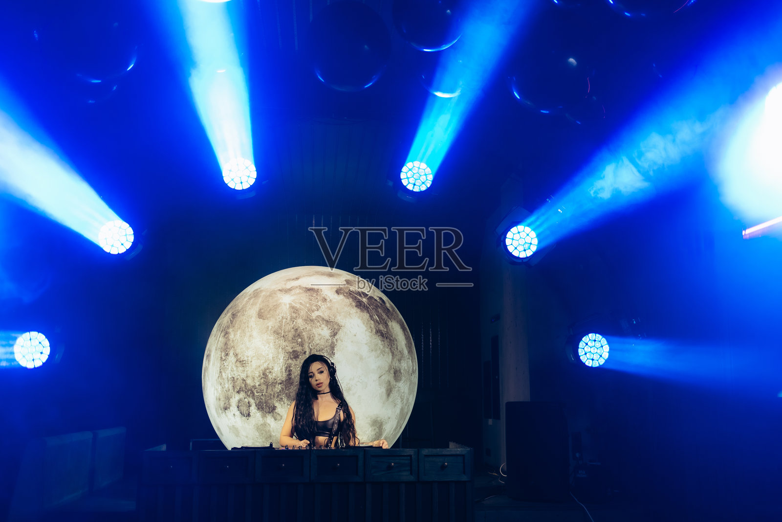 DJ表演与月亮背景和生动的聚光灯光束照片摄影图片