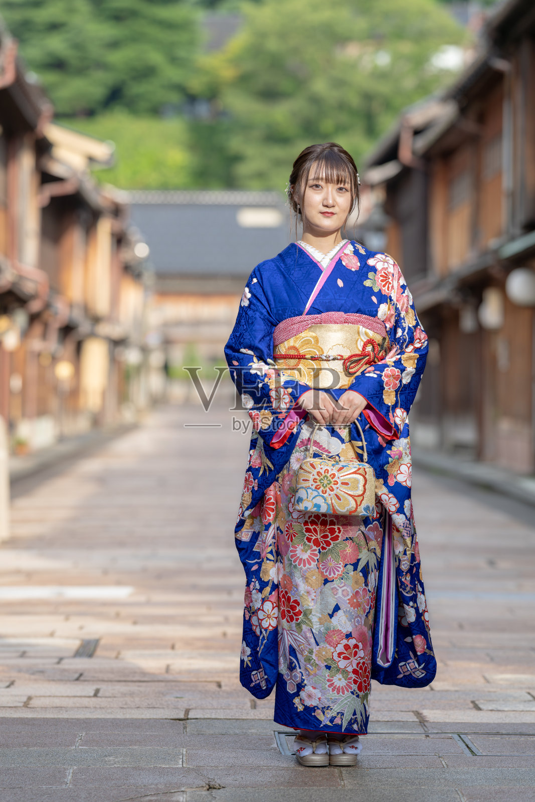 一位穿着蓝色和服的日本少女在日本某地区城市的传统街景中,雨天的夏日里静静站立。照片摄影图片