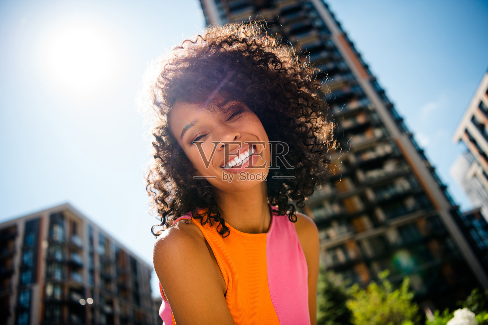 年轻漂亮的女性穿着色彩鲜艳的衣服,在城市公园外愉快地微笑着走路照片摄影图片