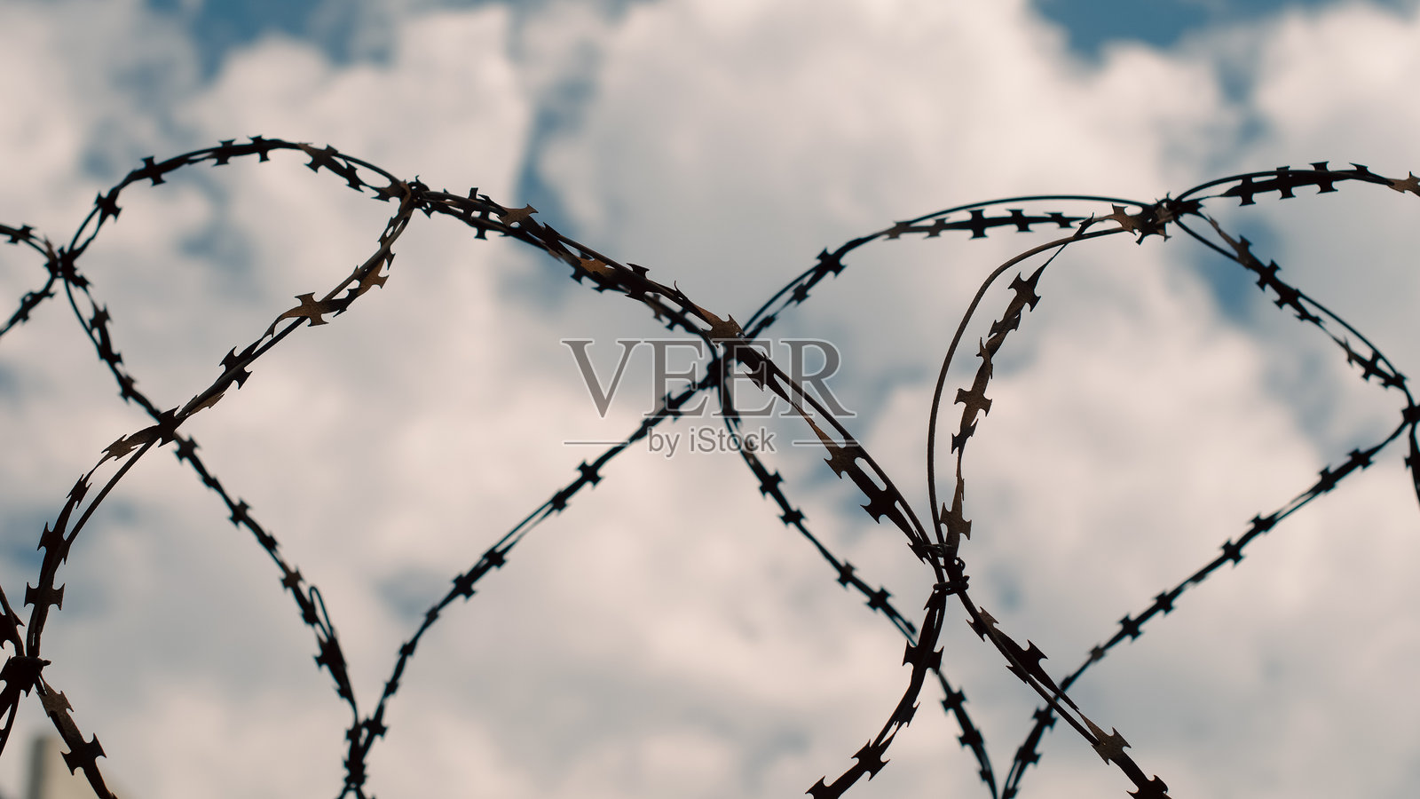 生锈的铁丝网在蓝天和白云的映衬下形成围栏照片摄影图片