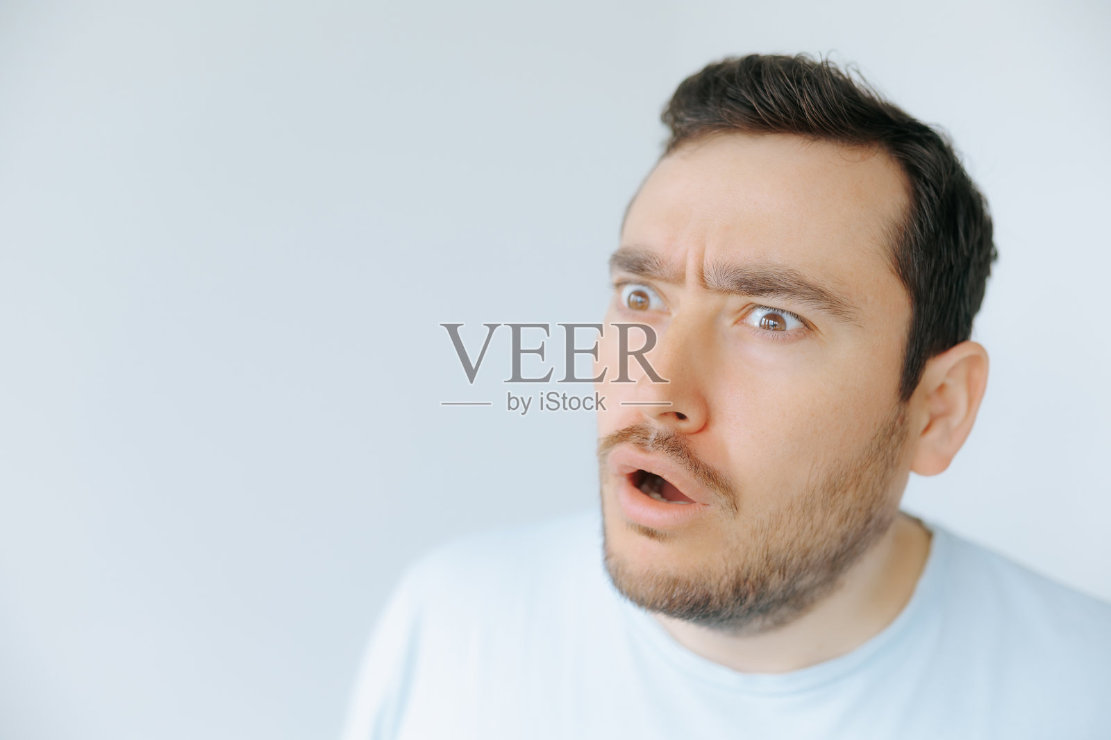 男子在简约的室内环境中白天表现出惊讶。照片摄影图片