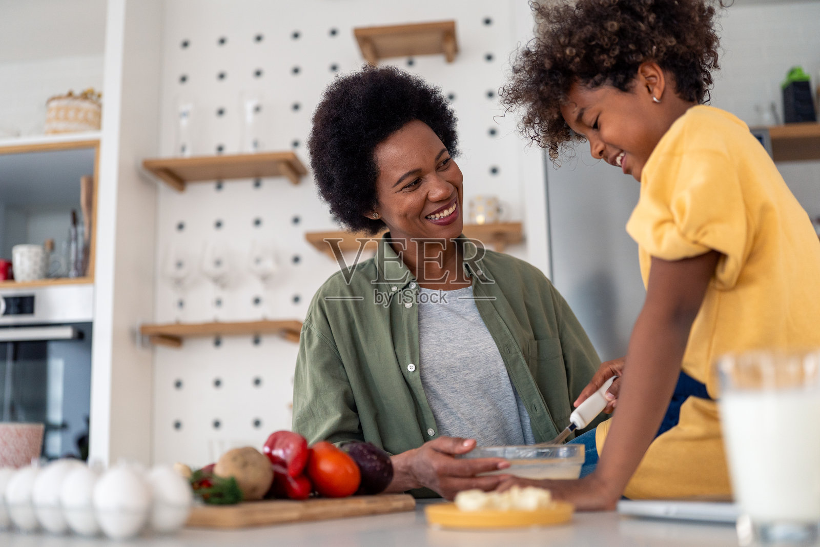 活泼的非洲母女在明亮的现代厨房里一起烹饪照片摄影图片