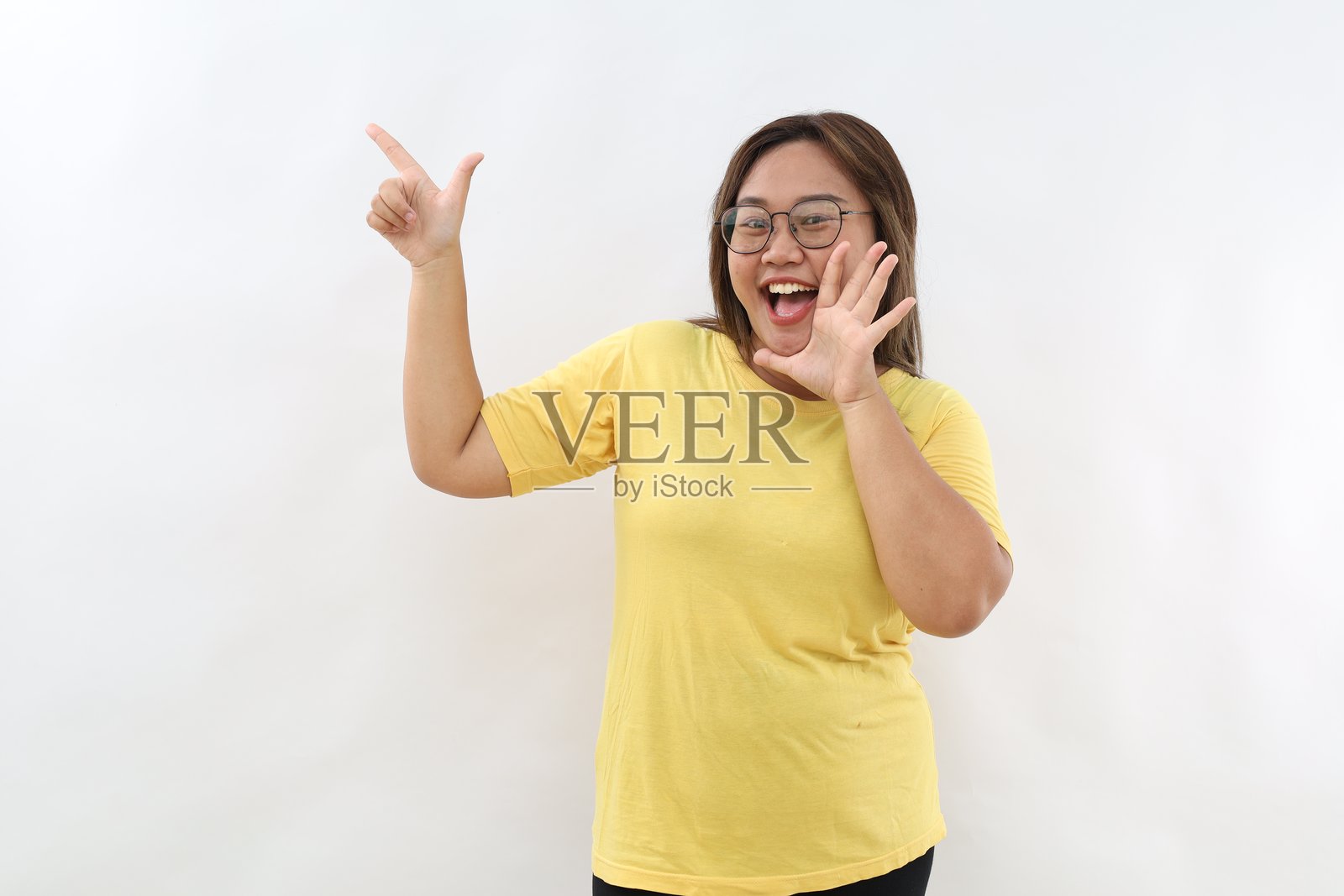 兴奋的年轻女性,表达积极情绪,指向空白的副本空间,展示愉快的事物,孤立在白色背景上照片摄影图片